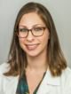 a headshot photograph of Dr. Daphna Spiegel, a white woman with dark blond shoulderlength straight hair and glasses and who is wearing a white doctor's coat with an emerald green shir tunderneath