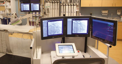 Figure 1. The CorPath 200 system in the cath lab: the bedside unit mounted on a bedrail, and the interventional cockpit 