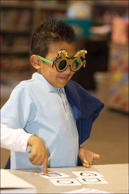 Four-year-old boy using a LEA symbol matching card during visual acuity testing at a vision screening. 