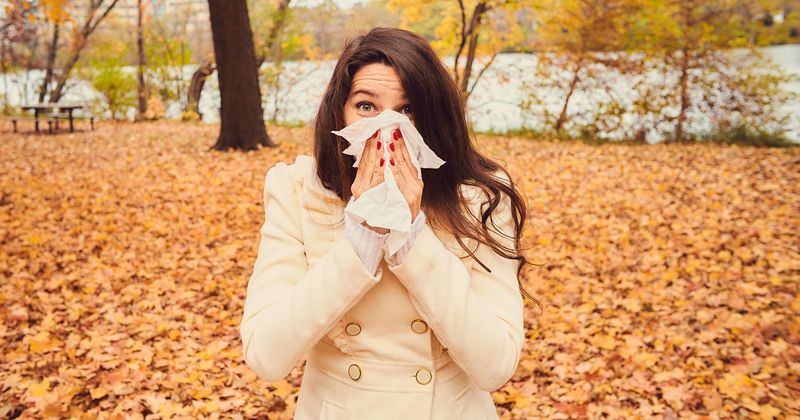 woman sneezing in the fall