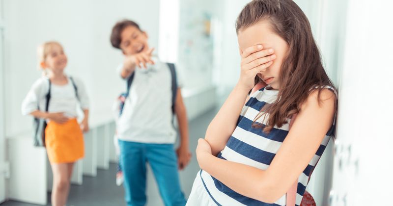 Girl being bullied by classmates at school.