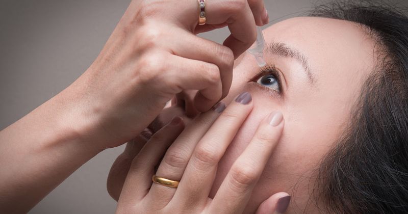 Woman giving herself eyedrops