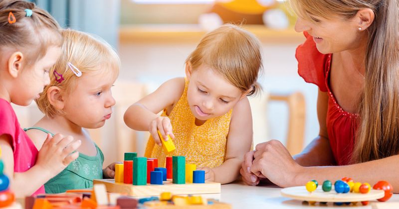 Children play with their teacher at a daycare center.