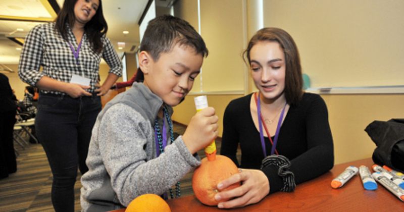 A child practices using an autoinjector on a grapefruit during a previous FACES.