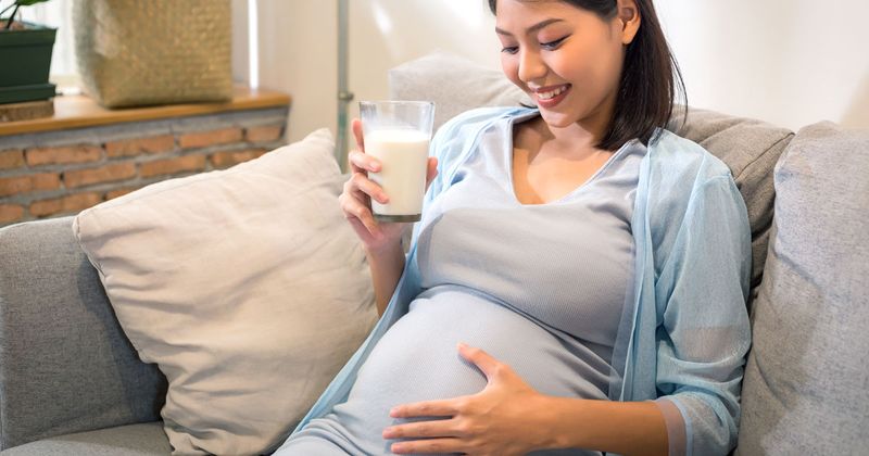 Pregnant Asian woman drinking milk. 