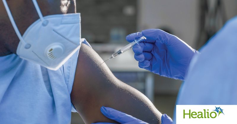 African American man wearing mask, receiving vaccine