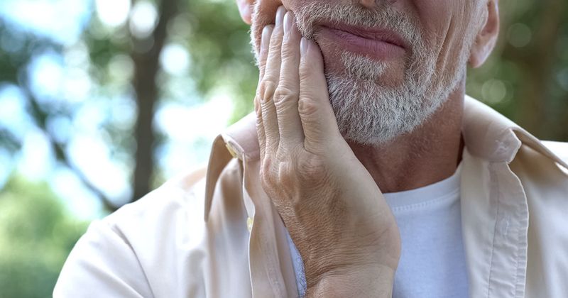 Older man experiencing what appears to be mouth pain