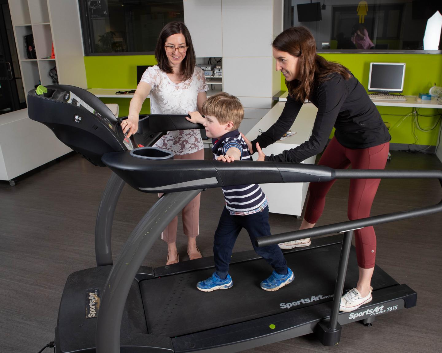 Photo of researchers with young boy on treadmill