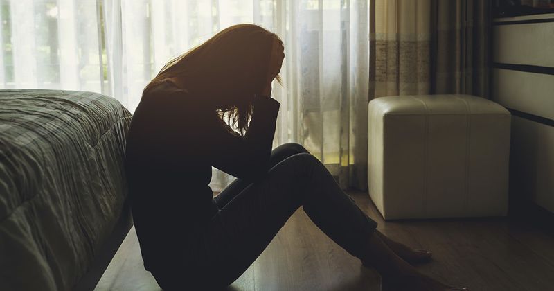 Woman crying and depressed on floor.