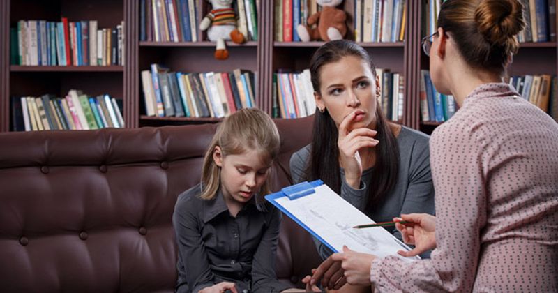 child looking sad next to mother