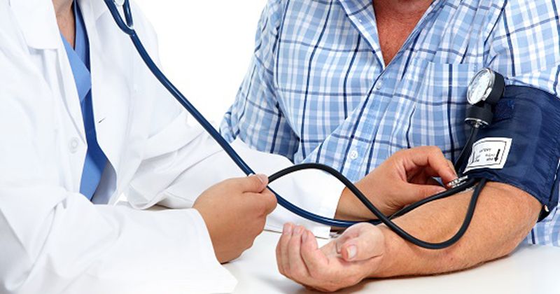 A doctor checks a male patient's blood pressure.