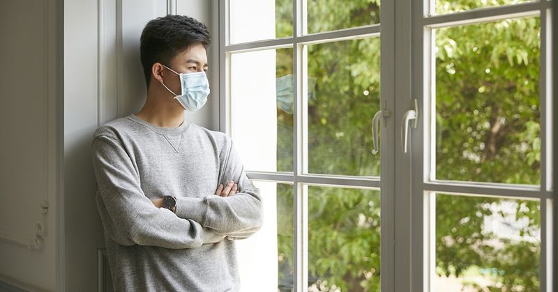 Young Asian man wearing mask inside the home.