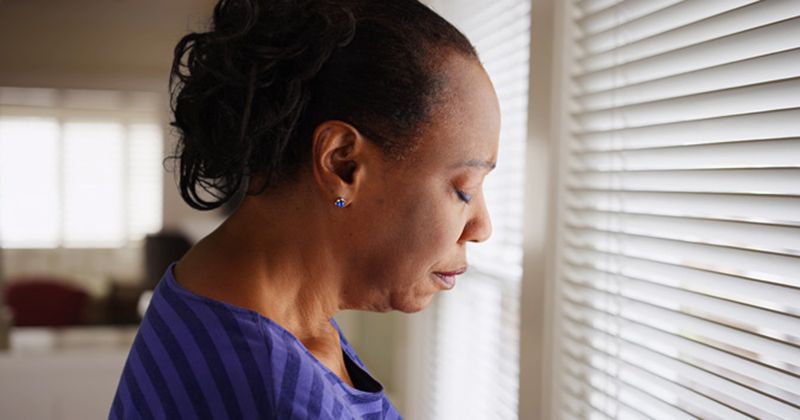 Woman who is sad standing near a window