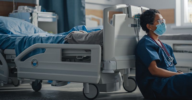 Medical worker sitting at the foot of hospital bed