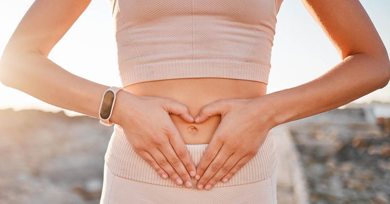 Woman hand heart over stomach