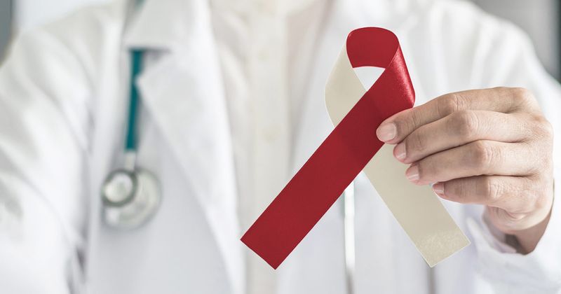 Doctor holding burgundy and white ribbon.