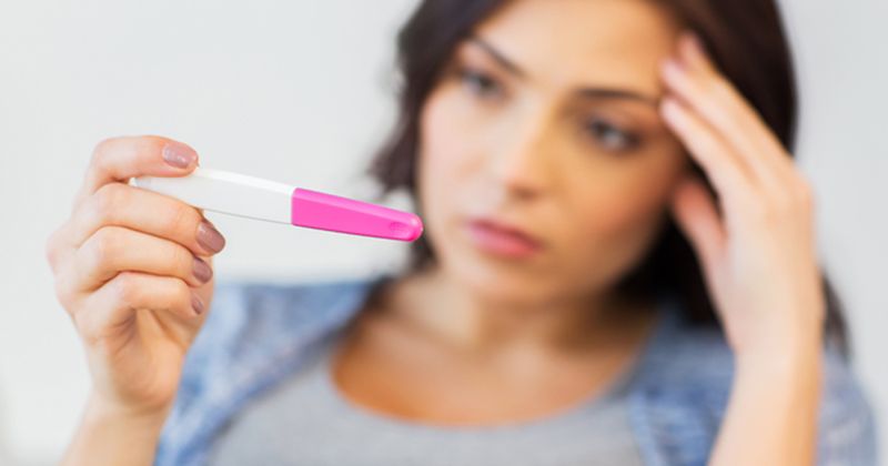 Photo of woman looking at pregnancy test