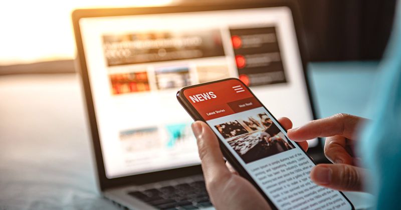 Online news on a smartphone. Mockup website. Woman reading news or articles in a mobile phone screen application at home. Newspaper and portal on internet