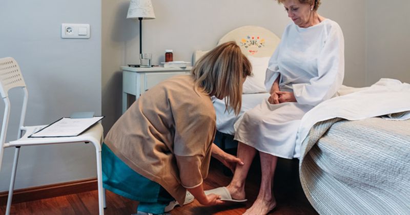 older woman being helped with slippers