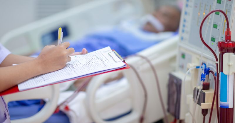 Doctor taking notes next to dialysis patient