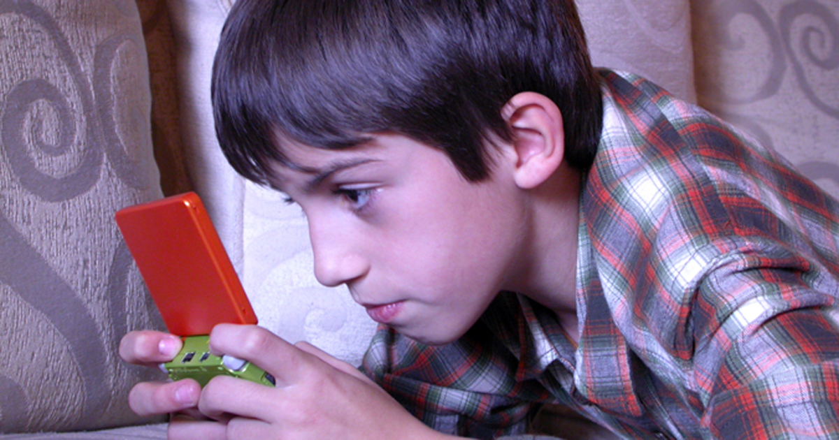 Photo of a young boy playing a handheld video game