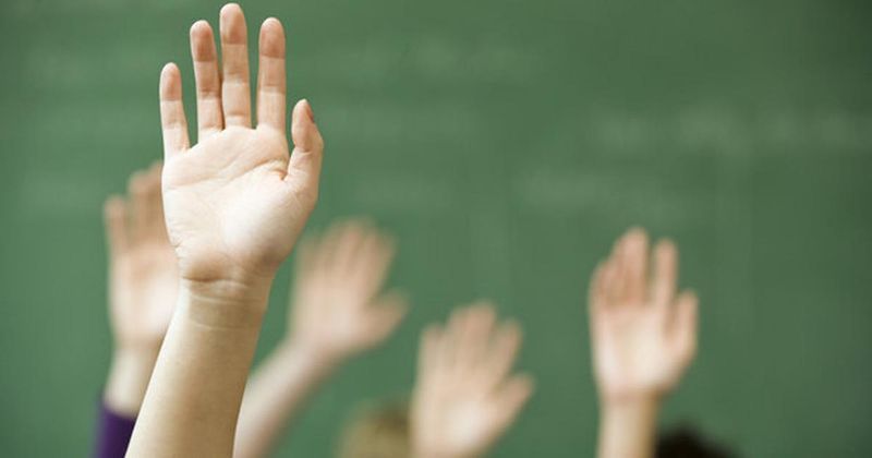 Children in classroom raising their hands.