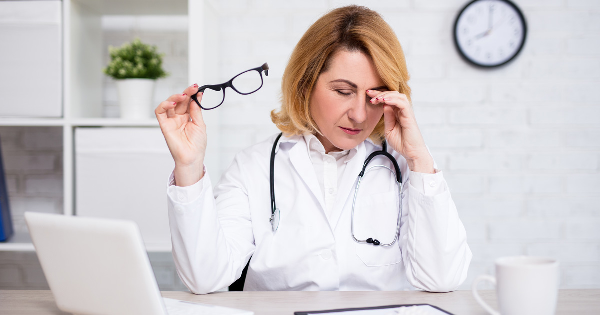 Photo of a frustrated woman doctor in a white coat with a stethoscope working on her laptop