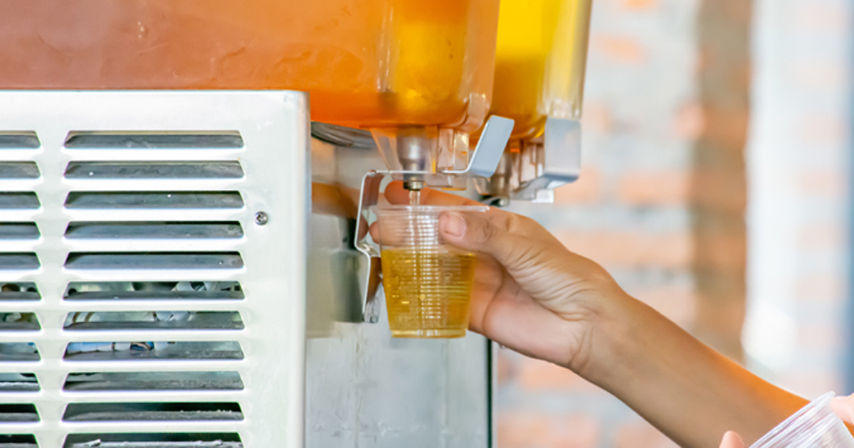 Person pouring tea from a tea dispenser