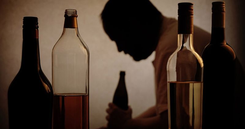 silhouette of man with alcohol bottles