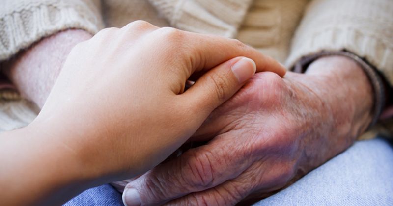 caregiver holds senior hand