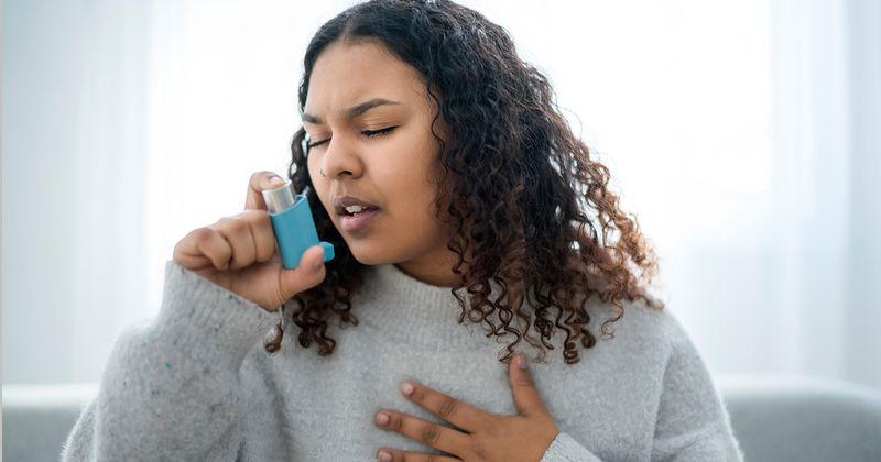 Black woman using an inhaler.