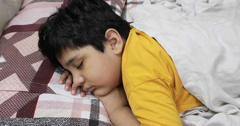 Young boy sleeping on bed.