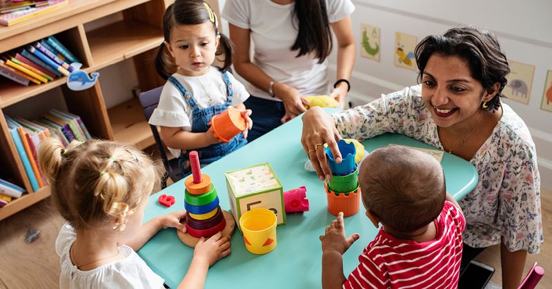 Children playing with teacher in a classroom.