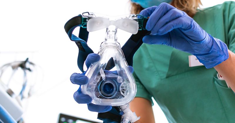 Nurse applying a mask for mechanical ventilation