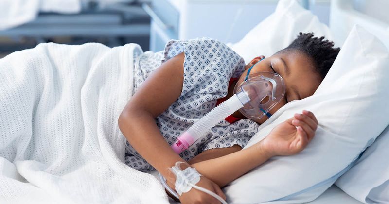 Child laying in hospital bed while receiving noninvasive ventilation.