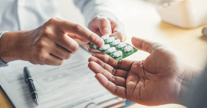 Doctor/physician handing pills to a patient.