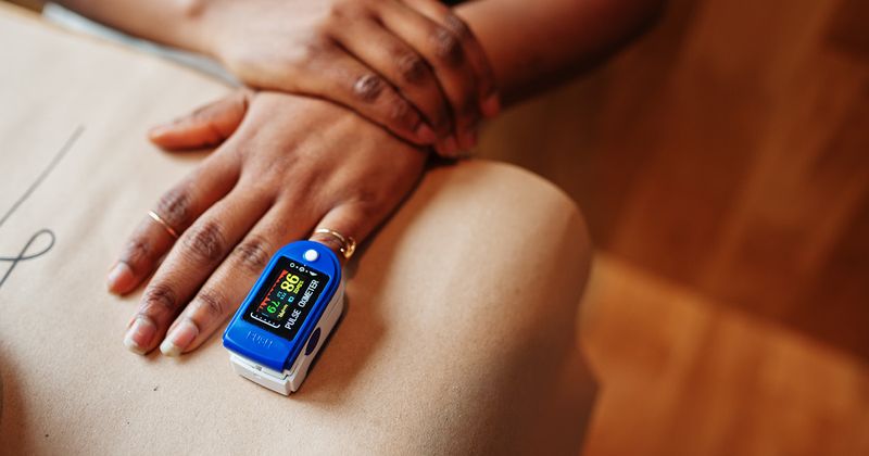 African American women with pulse oximeter on finger.