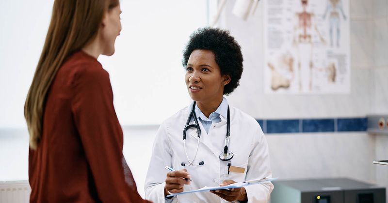 Black female doctor talking to a woman during medical appointment.