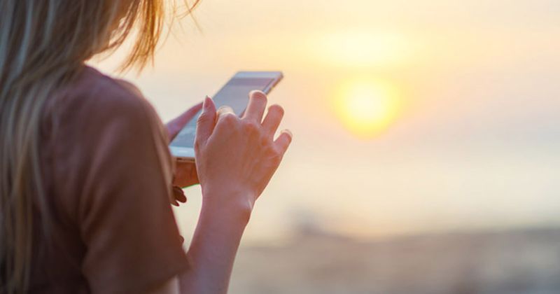 Female adolescent scrolls through a handheld mobile device.