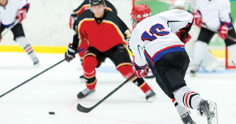 Hockey player in red jersey facing opposing player in white