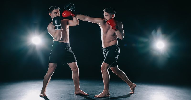 Two athletes standing toe to toe, one hitting the other