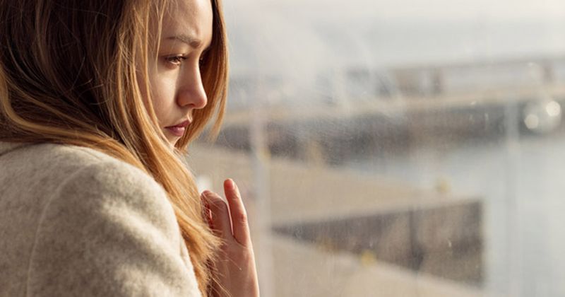 young woman looking out window